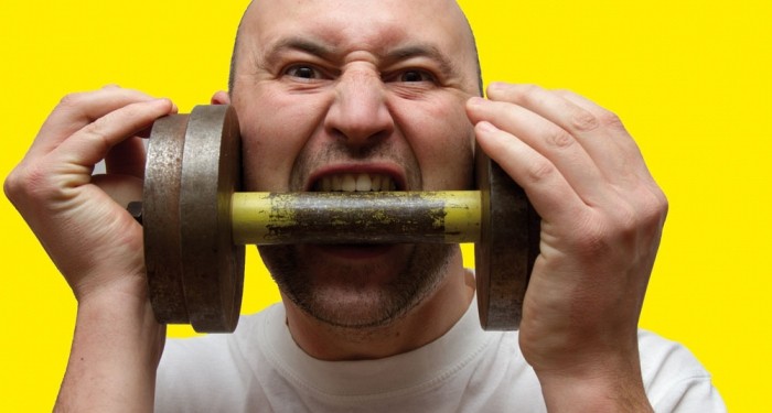 Mann beisst in Hantel